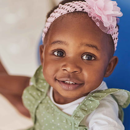 Little girl in green dress with pink bow.